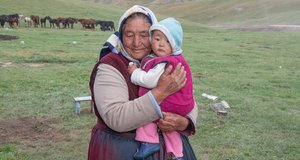 Eine Nomadin mit ihrem Enkel in den Bergen von Kirgistan